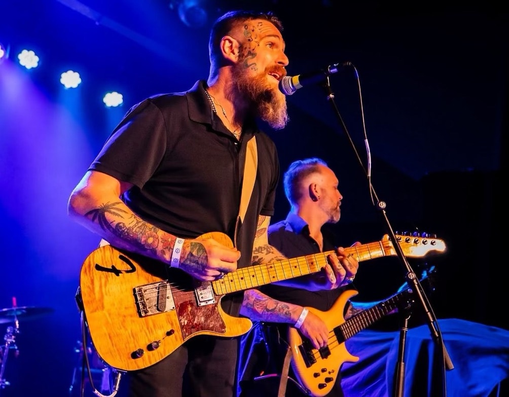 Andy Hughes performing electric guitar on stage